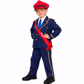 Junge im Kinder-Schaffner-Kostüm mit roter Schärpe über der Jacke, lächelnd, Hände in die Hüften gestützt, vor weißem Hintergrund.