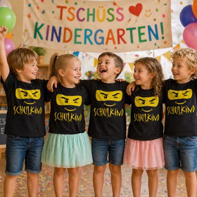 Kinder feiern Kindergarten-Abschied und tragen schwarze Schulkind T-Shirts mit gelbem Motiv vor buntem Banner „Tschüss Kindergarten“.