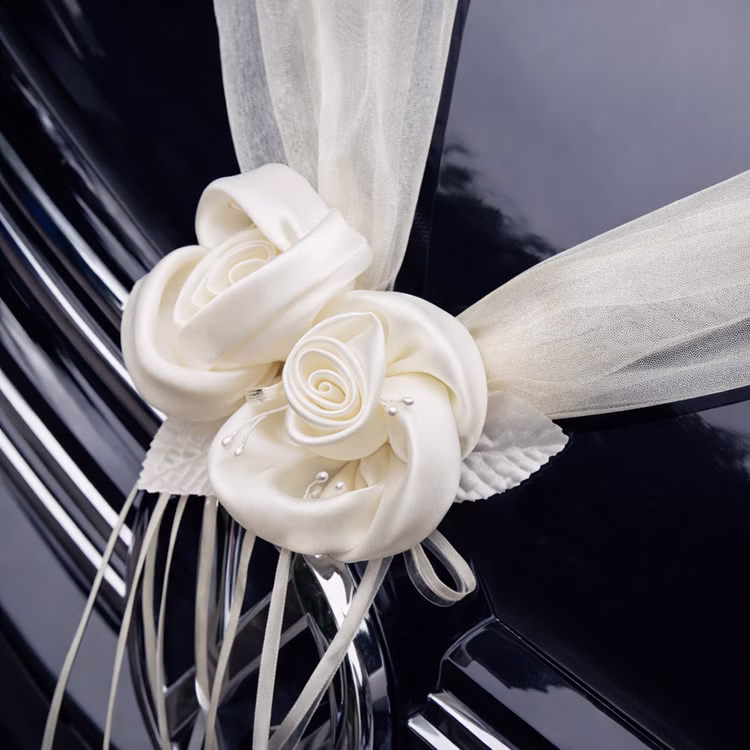 Autoschmuck Deko 2 Girlanden mit Blüten Creme 180 cm Motorhaube Hochzeitsauto Wedding Car Organza-Girlande mit Rosenblüten Dekoration Detailansicht zweier cremefarbener Rosenblüten aus Satinoptik mit transparentem Organza und dekorativen Schleifenbändern auf einer glänzenden Motorhaube.