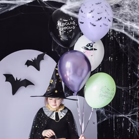 Halloween-Luftballons als Dekoration neben verkleidetem Mädchen und passender Partydekoration.