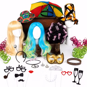 Fotobox Kostüm-Zubehör mit Perücken, Hüten, Maske, Schmuck und Accessoires dekorativ vor weißem Hintergrund arrangiert.