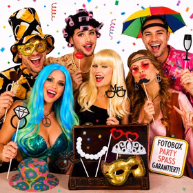 Fröhliche Gruppe mit bunten Perücken, Bierhut, Schirm-Hut und Party-Accessoires bei einer ausgelassenen Fotobox-Party mit Konfetti.