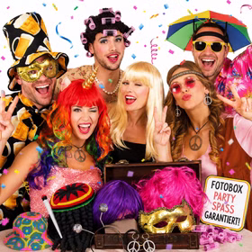 Fröhliche Gruppe mit bunten Perücken, Bierhut, Schirm-Hut und Party-Accessoires bei einer ausgelassenen Fotobox-Party mit Konfetti.