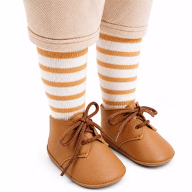 Braune Puppenschuhe mit Schnürung und gestreifte Kniestrümpfe ergänzen das liebevoll abgestimmte Outfit der Spielpuppe.