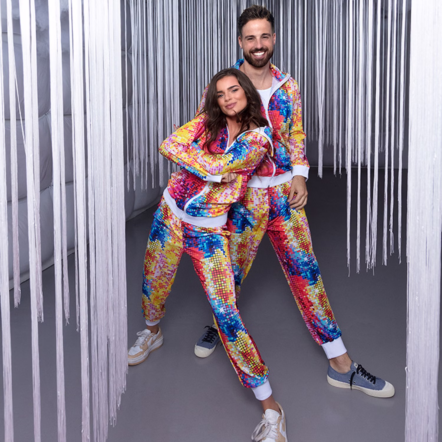 90er Jahre Jogginganzug Partnerkostüm Damen Herren Bunte 90er Jahre Jogginganzüge für Damen und Herren als auffälliges Partnerkostüm für Fasching und Retro-Mottopartys.