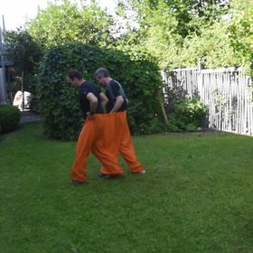 Wettrennen im Garten mit zwei Teams in grüner Doppelhose und orangefarbener Doppelhose