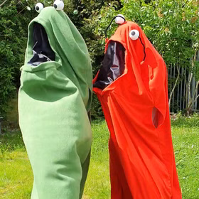 Monster Kostüme Yoko & Yuki für Erwachsene Paarkostüm Rot Grün Onesize Damen und Herren Paar- und Gruppenkostüm Fasching Karneval Mottoparty Halloween Grünes und Rotes Monster Kostüm stehen staunend im Garten