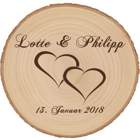 Personalisierte Baumscheibe mit Hochzeitsgravur als Dekoration auf einer festlich gedeckten Hochzeitstafel, im Hintergrund ein Brautpaar und Hochzeitsgäste in feierlicher Atmosphäre.