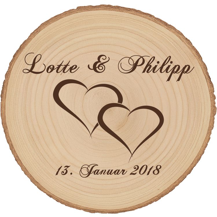 Personalisierte Baumscheibe mit Hochzeitsgravur als Dekoration auf einer festlich gedeckten Hochzeitstafel, im Hintergrund ein Brautpaar und Hochzeitsgäste in feierlicher Atmosphäre.