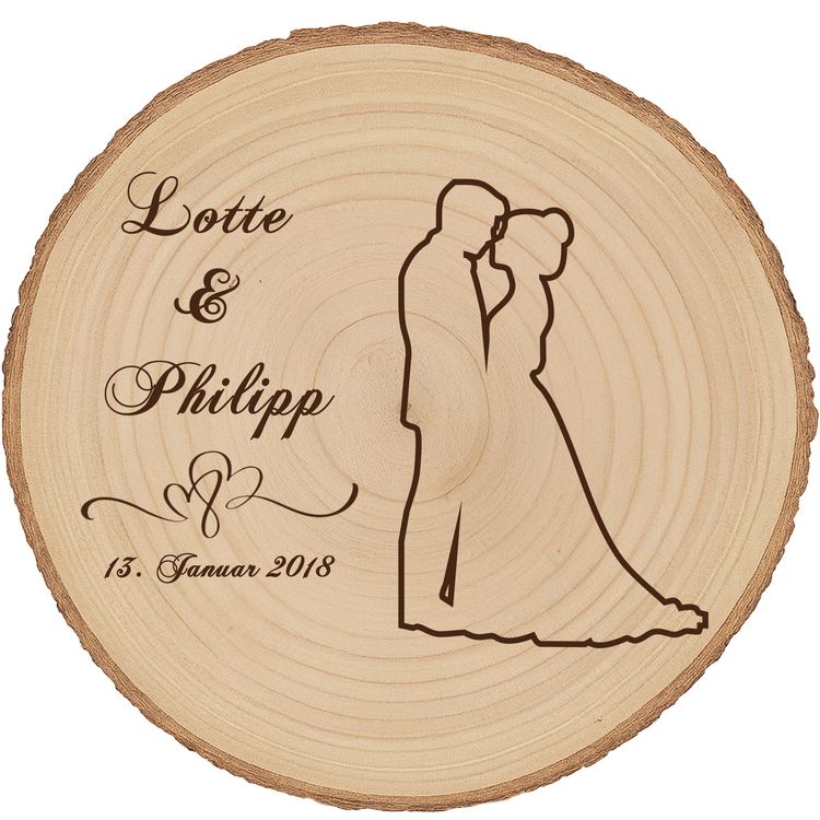 Braut und Bräutigam halten eine personalisierte Baumscheibe mit Hochzeitsgravur während der Zeremonie, im Hintergrund Blumen und Hochzeitsgesellschaft.