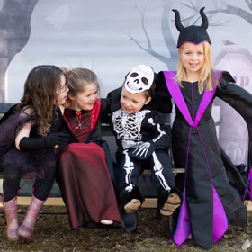 Halloween Skelett Kostüm Glow in the Dark mit Maske für Kinder Skelett-Kostüm Kinder in verschiedenen Halloween-Kostümen sitzen auf der Bank