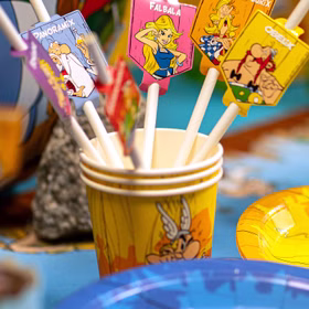 Asterix & Obelix Geburtstag Party-Set Tisch-Deko 32-tlg. Part-Deko Party-Zubehör Kindergeburtstag Comic-Helden Dekoration gedeckter Tisch Papierstrohhalme mit Asterix & Obelix Figurenmotiven in Partybecher auf farbenfroher Geburtstagstafel.