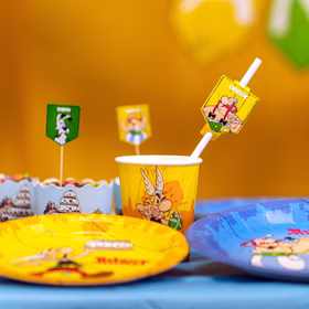 XXL Asterix & Obelix Geburtstag Party-Set Tisch-Deko 65-tlg. Part-Deko Kindergeburtstag Comic-Helden Dekoration gedeckter Tisch Asterix & Obelix Partybecher mit Comicmotiv auf Geburtstagstisch neben Tellern und Dekoration.