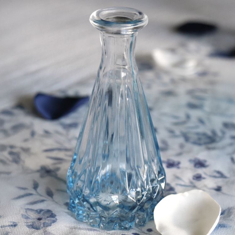 Kleine blaue Glasvase mit Rillenstruktur, leer, vor weißem Hintergrund.