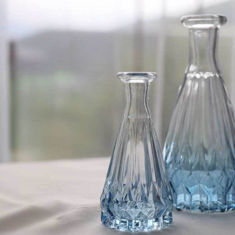 Kleine blaue Glasvase mit Rillenstruktur, leer, vor weißem Hintergrund.