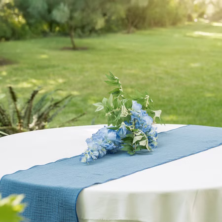 Tischläufer Stahlblau mit Waffelmuster 26 x 300 cm aus Baumwolle Tischdeko Tischdecke Deko-Ideen Geburtstag Hochzeit Wohntraum Runder Tisch mit blauem Baumwolle Tischläufer und blauer Blumendeko im Garten.