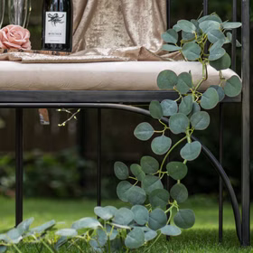 Eukalyptus Girlande 173 cm Grün Pflanzen Deko Hochzeit Geburtstag Basteln Kunstblume Tischdeko Deko-Ideen DIY Bastelbedarf Detailansicht der künstlichen Eukalyptus-Girlande an einer schwarzen Bank