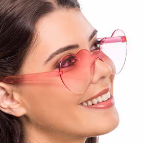 Nahaufnahme: Frau lächelt mit rosa Herz-Sonnenbrille in Herzform.