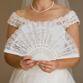 Eleganter weißer Spitzenfächer  im viktorianischen Stil aufgeklappt vor schwarzen Hintergrund von Vorne