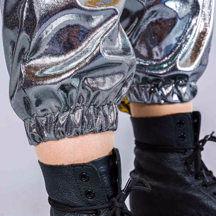 90er Jahre Space Kostüm Silver Flash Rave für Erwachsene Gr. M-XL Paarkostüm Gruppenkostüm Fasching Karneval 80er und 90er Mottoparty Nahaufnahme der Hosenbeine des silbernen Jogginganzugs, unten mit Gummibund über schwarzen Schnürstiefeln.