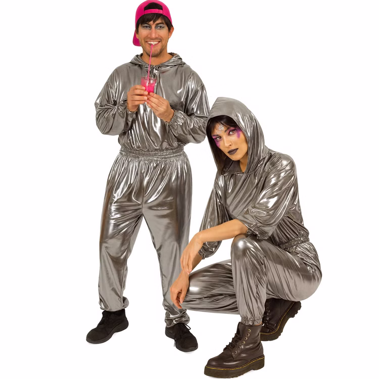 90er Jahre Space Kostüm Silver Flash Rave für Erwachsene Gr. M-XL Paarkostüm Gruppenkostüm Fasching Karneval 80er und 90er Mottoparty Mann und Frau tragen silberne Jogginganzüge mit Kapuze, er steht mit pinker Cap und Getränk, sie hockt mit auffälligem Make-up.