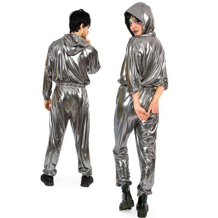 Mann und Frau tragen silberne Jogginganzüge mit Kapuze, er steht mit pinker Cap und Getränk, sie hockt mit auffälligem Make-up.