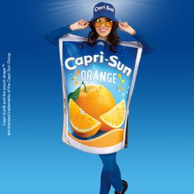 Frau im Capri-Sun® Orange Kostüm mit Tunika und Hut – witziges Getränkekostüm für Erwachsene.