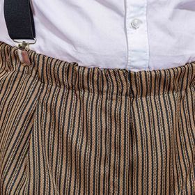 Mann in braun gestreifter Knickerbocker mit Weste, weißem Hemd und Schirmmütze von Vorne.