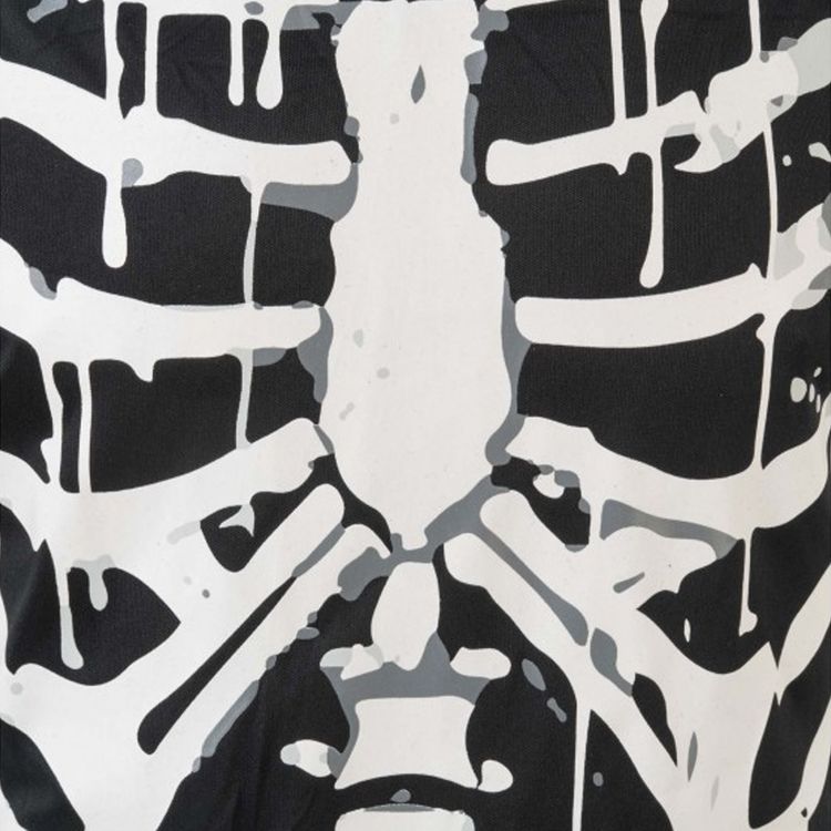 Junge im schwarzen Overall, der mit weißen Knochenteilen bedruckt ist von Vorne. Der Junge hat die Kapuze des Overalls auf dem Kopf.