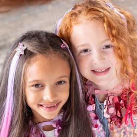 Bunte Haarsträhnen mit Clip 8 Stück Pink & Lila Prinzessin Fee Extensions für Kinder Geschenkidee Geburtstag Fasching Karneval Rollenspiel Verkleidung Zwei Mädchen mit bunten Haarsträhnen und glitzernden Sternclips lächeln in die Kamera.