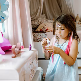 Bunte Haarsträhnen mit Clip 8 Stück Pink & Lila Prinzessin Fee Extensions für Kinder Geschenkidee Geburtstag Fasching Karneval Rollenspiel Verkleidung Kind lackiert sich die Nägel in Lila, trägt pinke Haarsträhnen mit Sternclips und ein hellblaues Kleid.