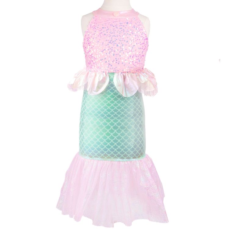 Mädchen trägt Meerjungfrauenkostüm und sitzt lächelnd auf einer alten Schatztruhe am Strand mit Meer im Hintergrund.