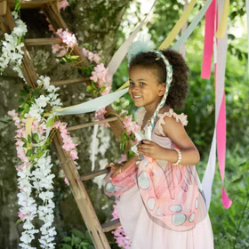 Schmetterling Kostüm Fee Rosalie Kleid mit Flügeln für Kinder 5-6 Jahre Tierkostüm Fasching Karneval Mottoparty Kindergeburtstag Ein Mädchen im rosa Schmetterlingskleid steigt eine Leiter hinauf, die mit Blumen geschmückt ist.