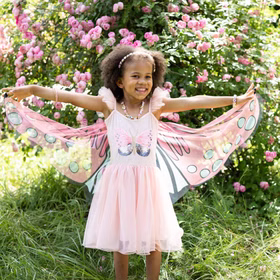 Schmetterling Kostüm Fee Rosalie Kleid mit Flügeln für Kinder 5-6 Jahre Tierkostüm Fasching Karneval Mottoparty Kindergeburtstag Ein Mädchen im Schmetterlingskleid breitet die rosa Flügel im Garten vor einer Rosenhecke weit aus.
