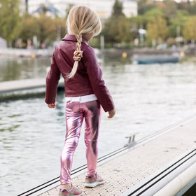 Leggings Rosa Metallic Fee Prinzessin Kostüm-Zubehör für Kinder 3-8 Jahre Kostüm-Zubehör Fasching Karneval Mottoparty Geburtstag Kinderfasching Rückansicht eines Mädchens in pinkfarbener Metallic-Leggings und weinroter Jacke, das auf einem Steg am Wasser entlangläuft.