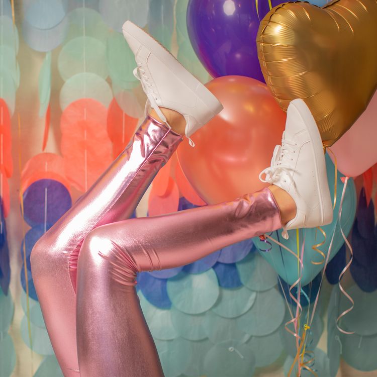 Eine glänzende pinkfarbene Kinderleggings liegt einzeln gefaltet auf weißem Hintergrund.