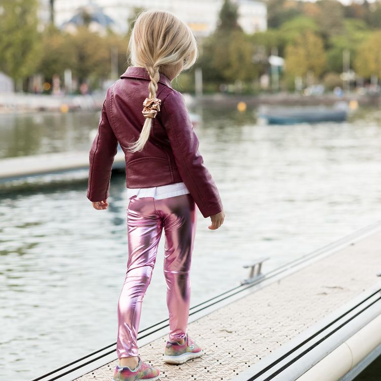 Eine glänzende pinkfarbene Kinderleggings liegt einzeln gefaltet auf weißem Hintergrund.