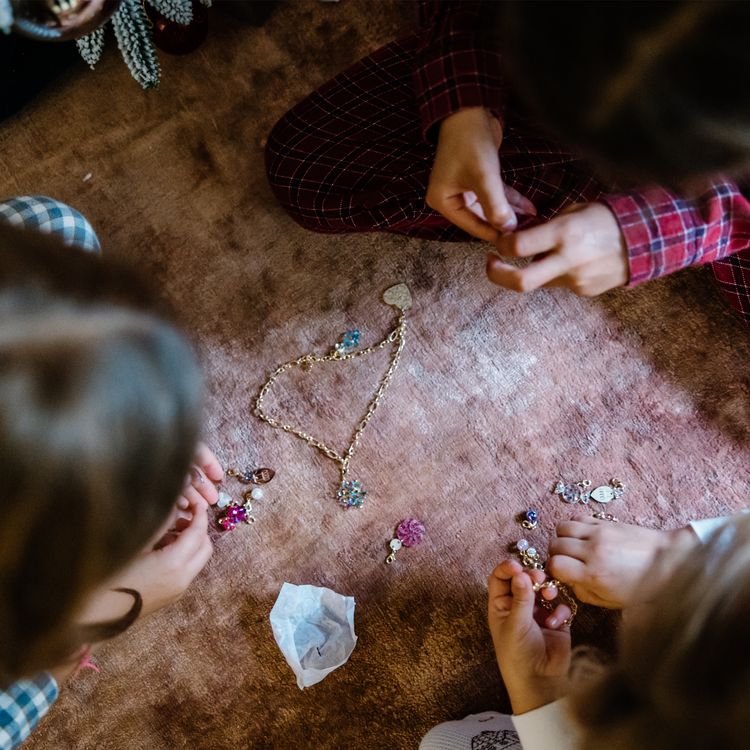 Schmuck Adventskalender Armband & Kette 22 Anhänger Weihnachts-Party für Kinder Adventskalender mit geöffnetem Türchen, davor die enthaltenen Schmuckteile dekorativ angeordnet.
