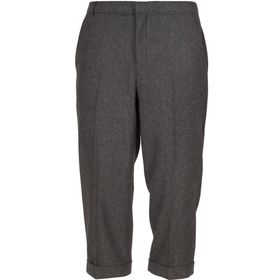 Ein Mann trägt ein komplettes Kostüm im 20er-Jahre-Stil mit grauer Weste, Knickerbockerhose, weißem Hemd, schwarzer Krawatte und schwarzen Schuhen.
