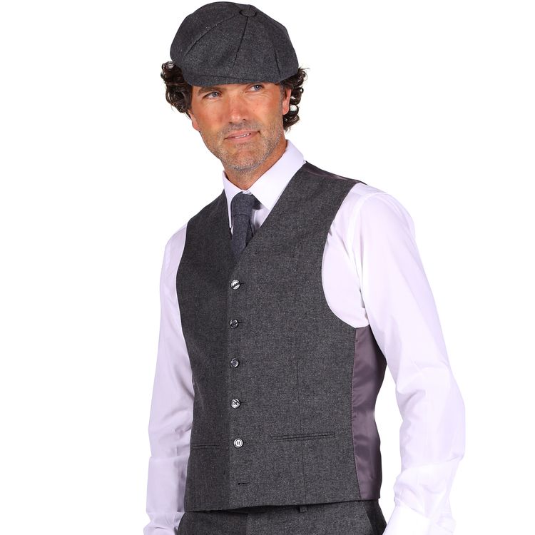Ein Mann trägt ein komplettes Kostüm im 20er-Jahre-Stil mit grauer Weste, Knickerbockerhose, weißem Hemd, schwarzer Krawatte und schwarzen Schuhen.