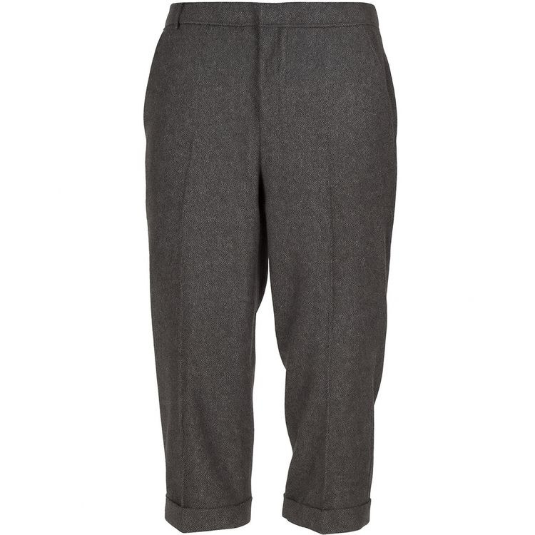 Ein Mann trägt ein komplettes Kostüm im 20er-Jahre-Stil mit grauer Weste, Knickerbockerhose, weißem Hemd, schwarzer Krawatte und schwarzen Schuhen.