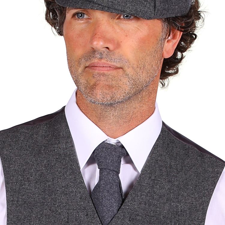 Ein Mann trägt ein komplettes Kostüm im 20er-Jahre-Stil mit grauer Weste, Knickerbockerhose, weißem Hemd, schwarzer Krawatte und schwarzen Schuhen.