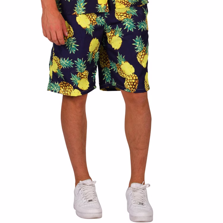 Hawaii Shorts mit Ananas-Motiv kurze Hosen Urlaubs-Outfit für Herren Gr. M-XXL Kostüm-Zubehör Beachparty Strandurlaub Fasching Karneval Mottoparty Ein Mann trägt eine schwarze Shorts mit gelbem Ananasmuster, kombiniert mit weißen Sportschuhen.