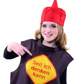 Gewürz Kostüm Spicy Lebensmittel Extra Würze für Erwachsene Onesize Paar- und Gruppenkostüm Spaßkostüm Fasching Karneval Mottoparty Frau mit roter Flaschenmütze zeigt lachend auf den gelben Brustaufdruck „Seit ich denken kann“
