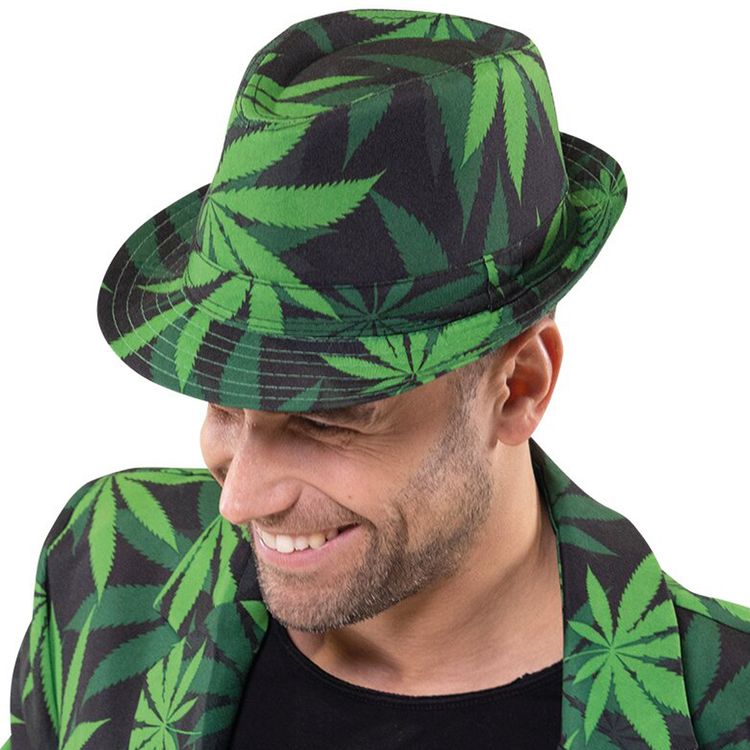 Ein Mann trägt einen Fedora-Hut mit grünem Hanfblattmuster und schaut lachend nach unten.