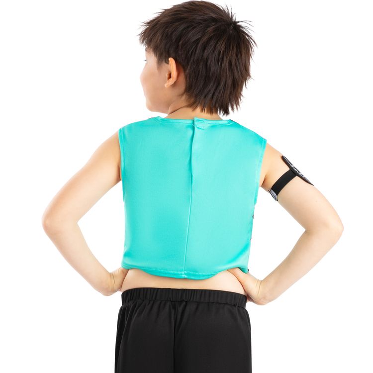 Kind trägt ein KPop Demon Hunters Kinderkostüm mit türkisfarbenem Crop-Top, bedruckter Hose in Blau-Gelb und schwarzen Sneakers. Das Kind steht frontal mit Händen in die Hüften gestützt vor weißem Hintergrund mit Serienlogo.