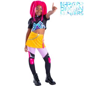 Kind trägt das Mira Core KPop Demon Hunters Kostüm mit pinker Perücke, schwarzem Crop-Top, gelbem Rock und Leggings und zeigt eine selbstbewusste Pose vor weißem Hintergrund.
