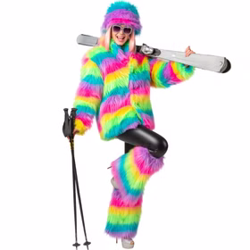 Frau trägt bunte Plüsch-Stulpen mit langem Regenbogenflor und dazu einen passenden farbigen Plüschmantel und eine Plüschmütze. Über der Schulter trägt sie Skier und in der anderen Hand Skistöcke.