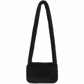 Schwarze Plüschtasche mit langem Schulterriemen und Reißverschluss aus Kunstfell vor weißem Hintergrund.