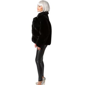 ine Frau trägt eine kurze schwarze Plüschjacke und lächelt in die Kamera. Die Jacke ist voluminös und hat einen breiten Kragen.